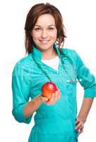 Young lady doctor is holding a red apple