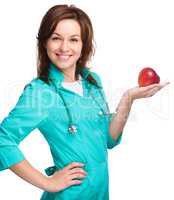 Young lady doctor is holding a red apple