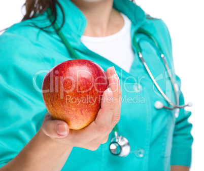 Young lady doctor is holding a red apple