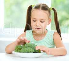 Cute little girl is eating green grapes