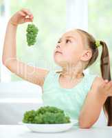 Cute little girl is eating green grapes