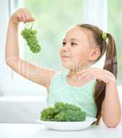 Cute little girl is eating green grapes