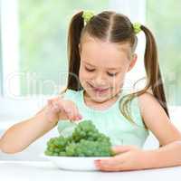 Cute little girl is eating green grapes