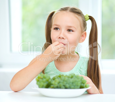 Cute little girl is eating green grapes