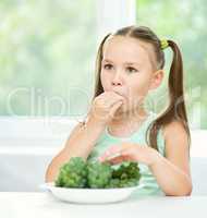 Cute little girl is eating green grapes