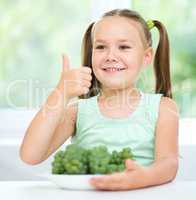Cute little girl is eating green grapes
