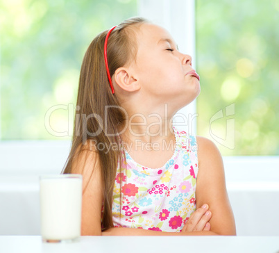 Sad little girl with a glass of milk