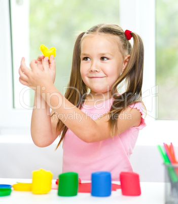 Little girl is playing with plasticine