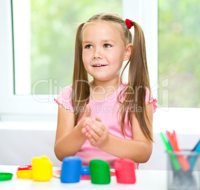 Little girl is playing with plasticine