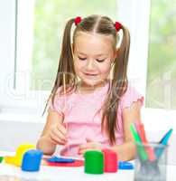 Little girl is playing with plasticine