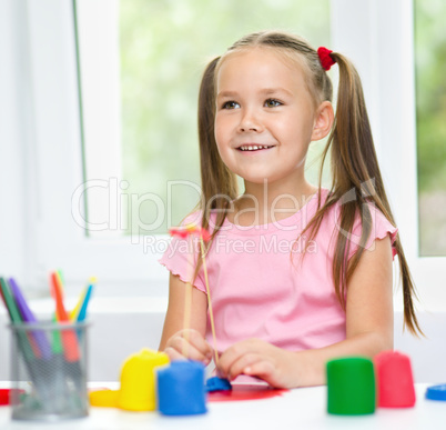 Girl is having fun while playing with plasticine