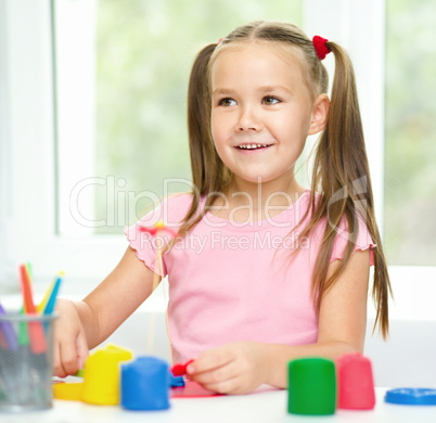 Girl is having fun while playing with plasticine