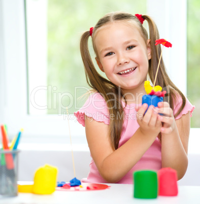 Little girl is playing with plasticine