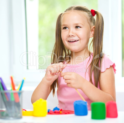 Girl is having fun while playing with plasticine