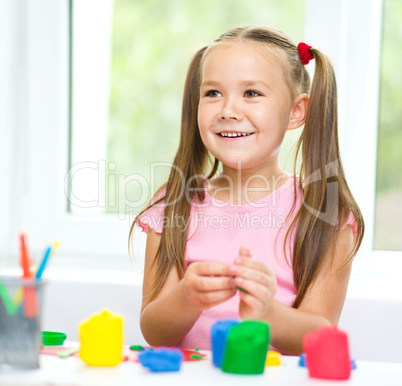 Girl is having fun while playing with plasticine