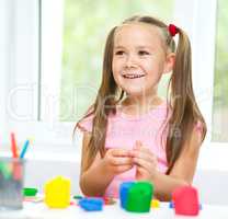 Girl is having fun while playing with plasticine