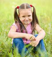 Portrait of a little girl sitting on green grass