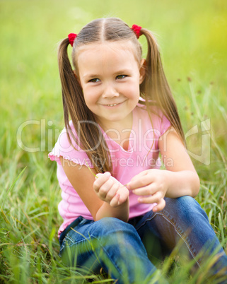 Portrait of a little girl sitting on green grass