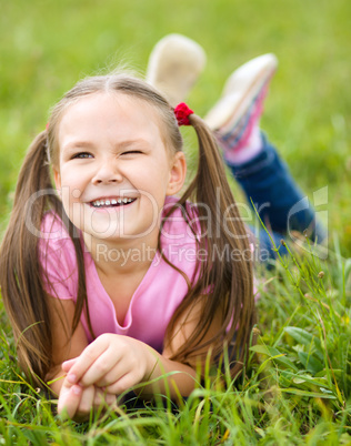 Portrait of a little girl laying on green grass