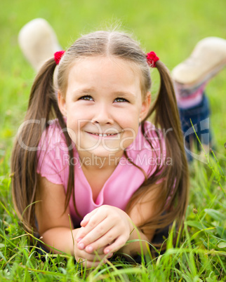 Portrait of a little girl laying on green grass