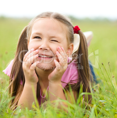 Portrait of a little girl laying on green grass