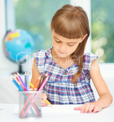 Little girl is drawing using pencils