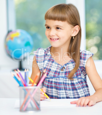 Little girl is drawing using pencils