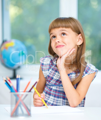 Little girl is drawing using color pencils