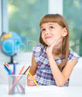 Little girl is drawing using color pencils