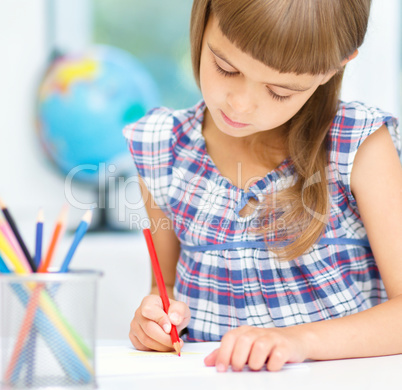 Little girl is drawing using pencils