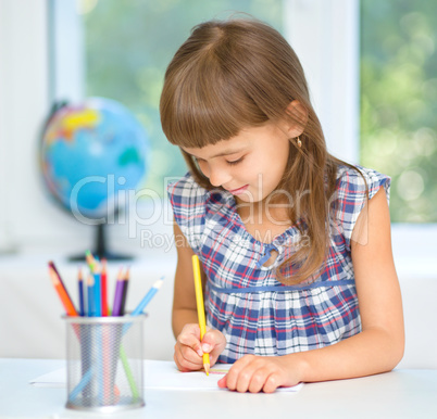 Little girl is drawing using pencils