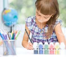 Little girl is painting with gouache