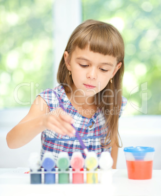 Little girl is painting with gouache