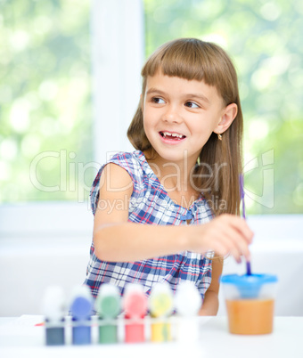 Little girl is painting with gouache