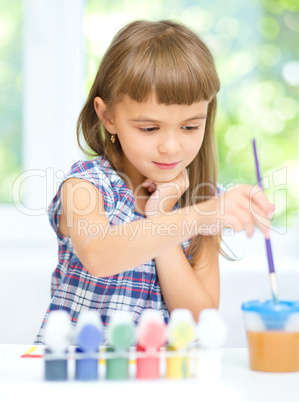 Little girl is painting with gouache