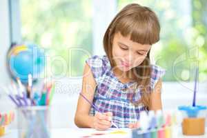 Little girl is painting with gouache