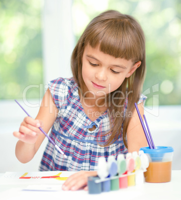 Little girl is painting with gouache