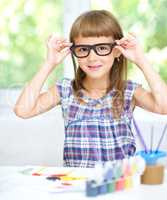 Little girl is painting with gouache