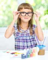 Little girl is painting with gouache