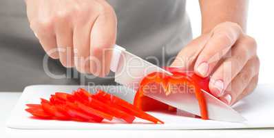 Cook is chopping bell pepper