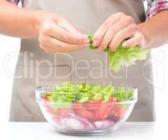 Cook is tearing lettuce while making salad