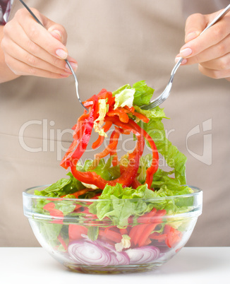 Cook is mixing salad