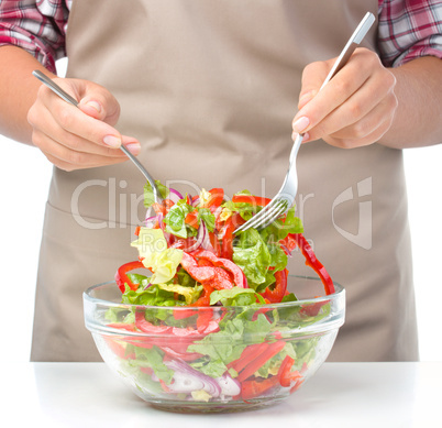 Cook is mixing salad