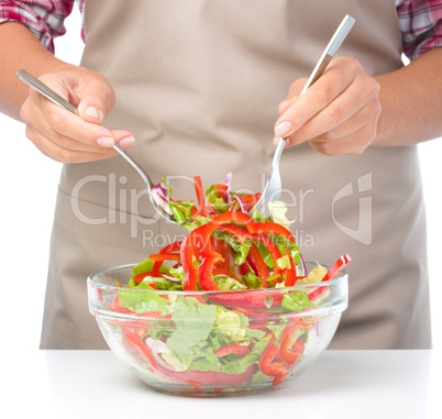 Cook is mixing salad