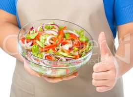 Cook is holding a big bowl with fresh salad