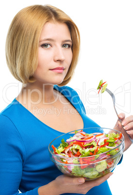 Young attractive woman is eating salad using fork