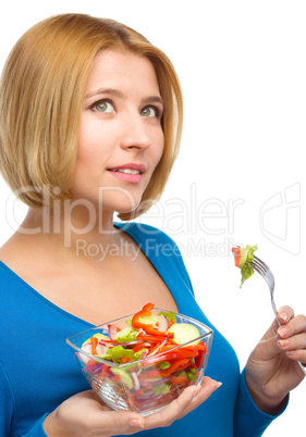 Young attractive woman is eating salad using fork