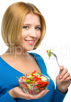 Young attractive woman is eating salad using fork