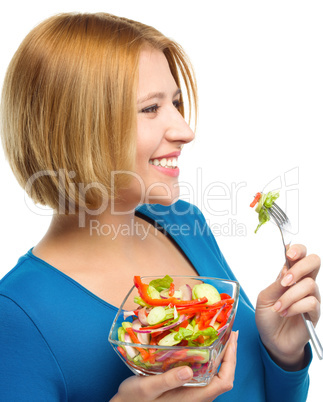 Young attractive woman is eating salad using fork