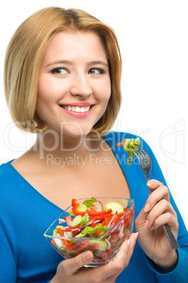 Young attractive woman is eating salad using fork